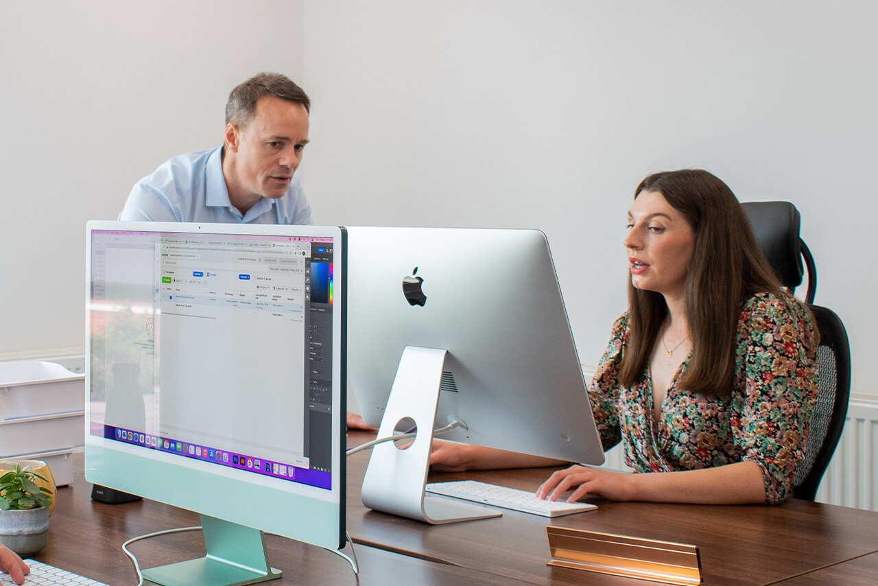 Man and woman looking at computer screen updating websites